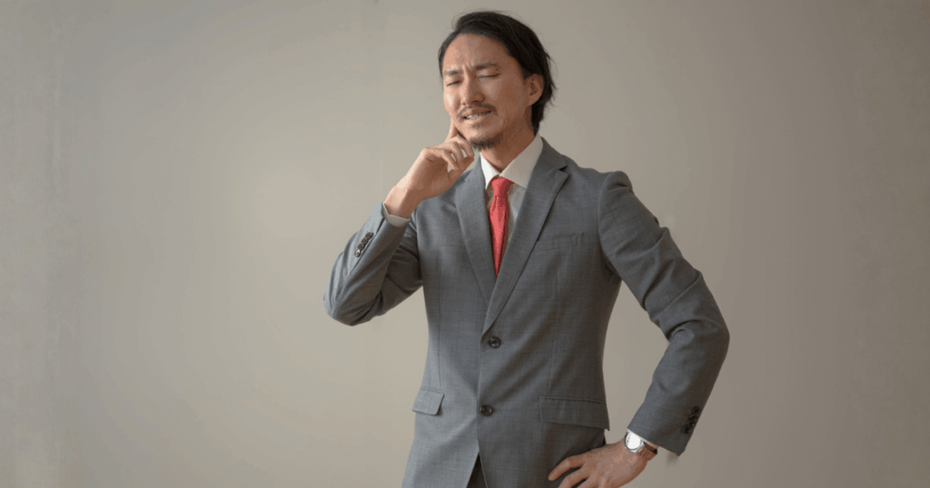 親知らず抜歯後の痛みや違和感に悩み、頬に手を当てている男性のイメージ