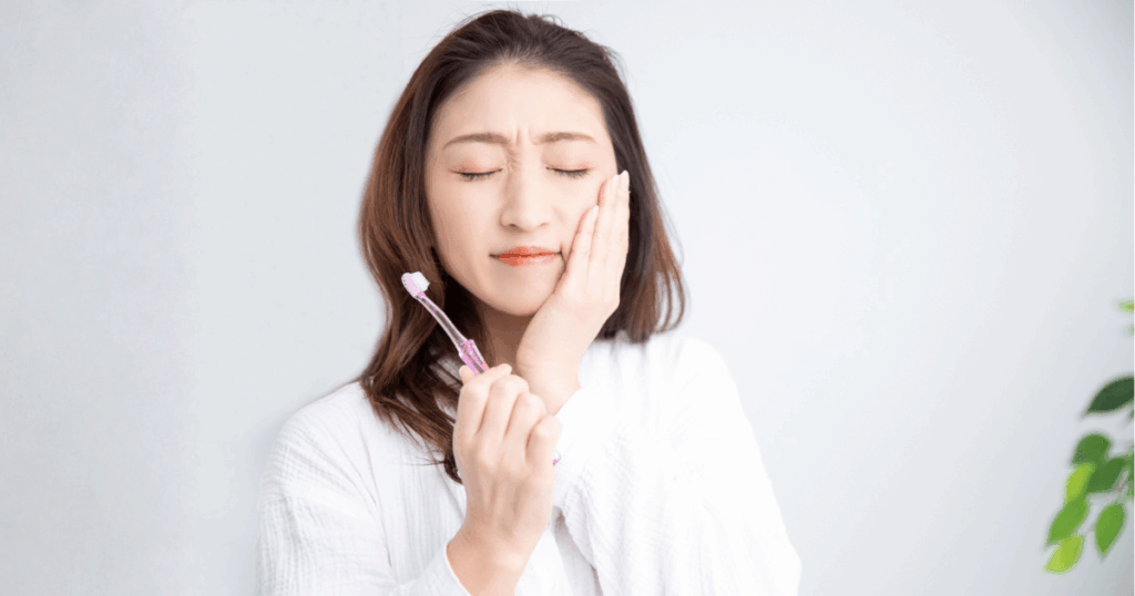 親知らずの痛みや抜歯後の後悔をイメージした、頬を押さえる女性の写真
