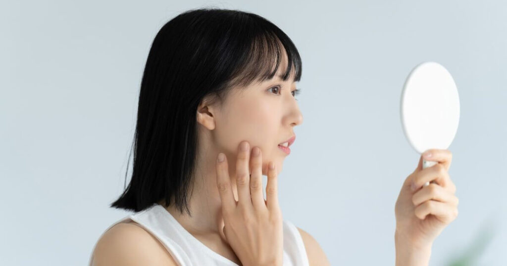 腫れていないか鏡で確認する女性